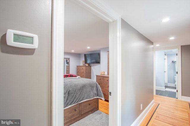 bedroom with baseboards, ensuite bath, wood finished floors, and recessed lighting