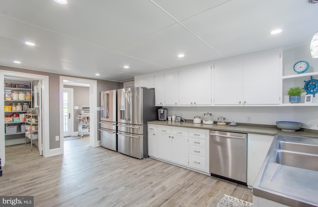 kitchen with stainless steel appliances, light wood-type flooring, open shelves, and white cabinets