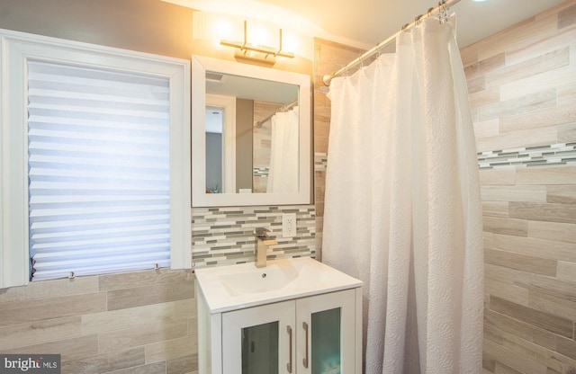 full bathroom with a tile shower, backsplash, and vanity