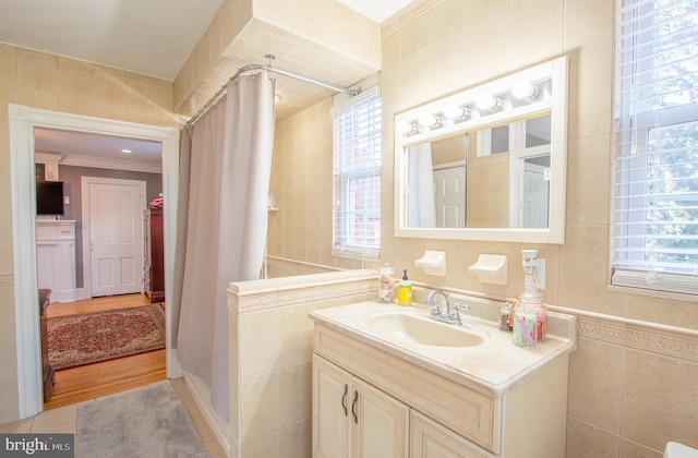 bathroom with a stall shower, crown molding, tile walls, and vanity