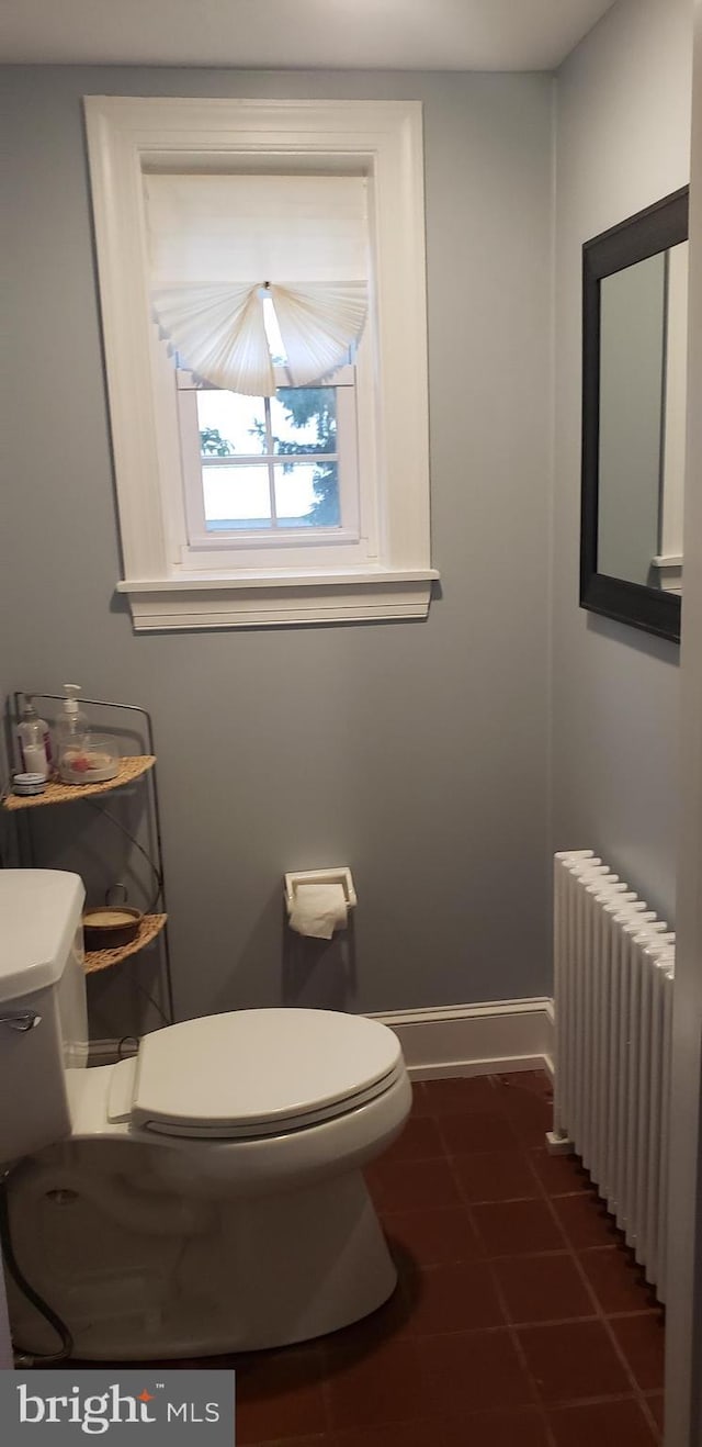 bathroom with toilet, radiator heating unit, and baseboards