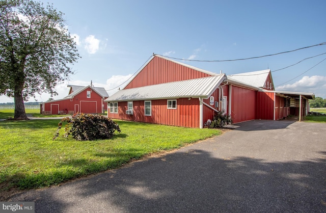 view of front of property featuring an outbuilding, metal roof, a front lawn, and a barn