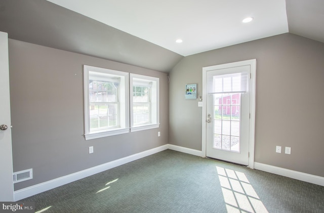 entryway featuring lofted ceiling, dark carpet, visible vents, and baseboards