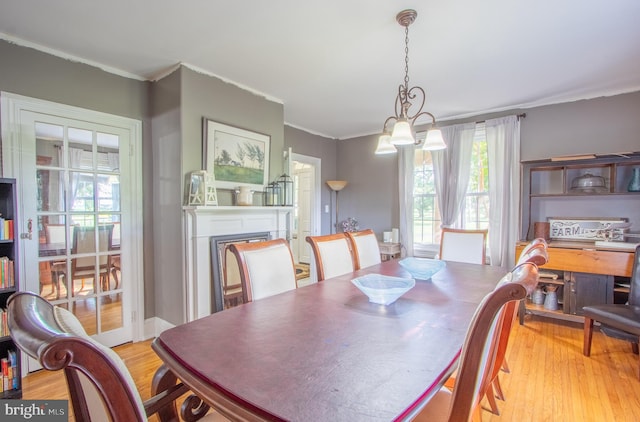 dining room with light wood-style floors, a fireplace, and ornamental molding