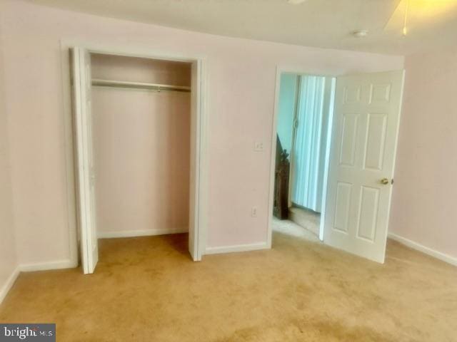 unfurnished bedroom with light carpet and a closet