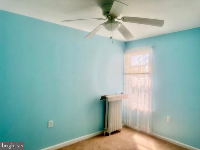 carpeted spare room with ceiling fan and radiator heating unit