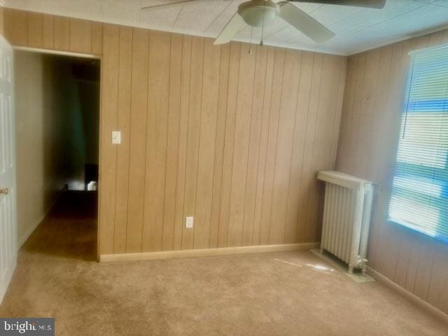 unfurnished room with ceiling fan, light colored carpet, and radiator heating unit