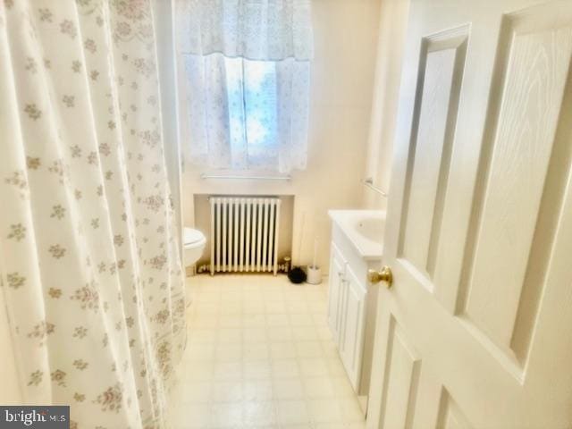 bathroom featuring radiator heating unit, a shower with shower curtain, vanity, tile patterned flooring, and toilet