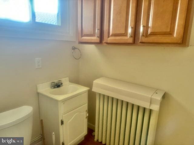 bathroom with toilet, vanity, and radiator