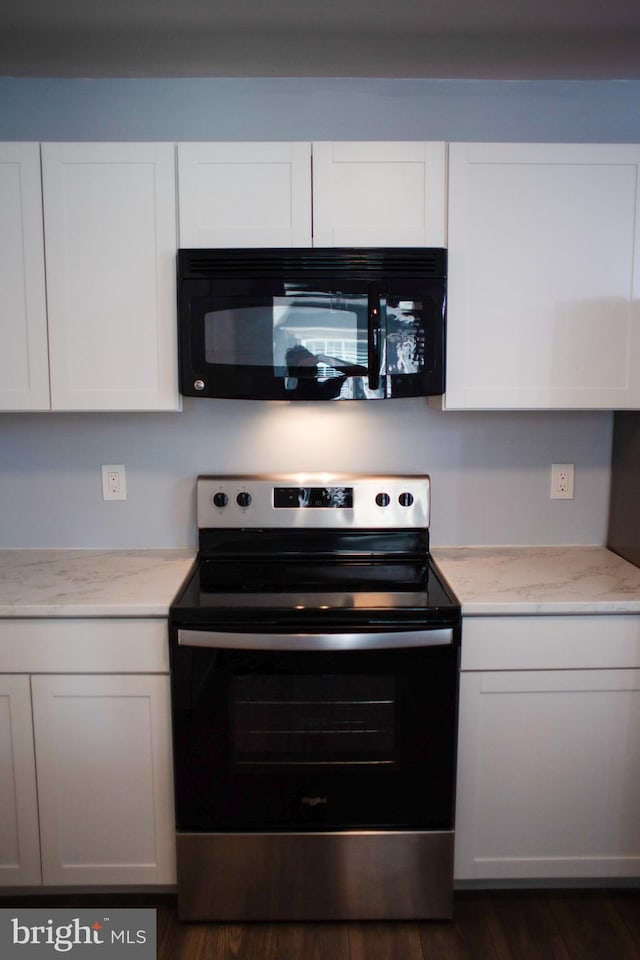 kitchen with light stone countertops, white cabinetry, dark hardwood / wood-style flooring, and stainless steel range with electric cooktop