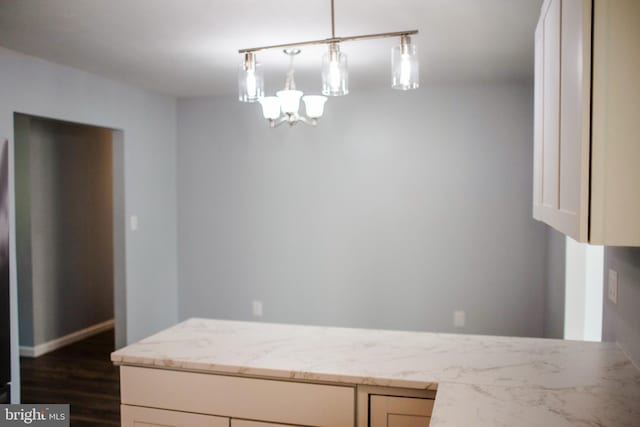 kitchen featuring dark wood-type flooring, hanging light fixtures, light stone countertops, and a chandelier