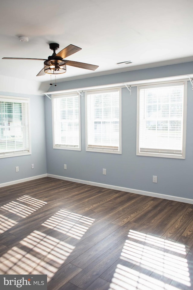 spare room with plenty of natural light, ceiling fan, and dark hardwood / wood-style floors