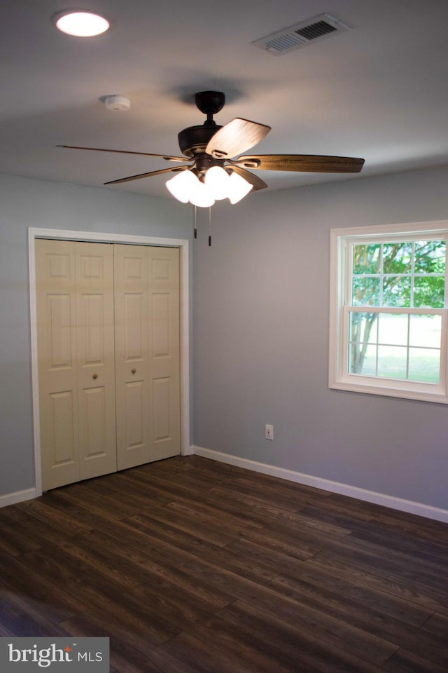 unfurnished bedroom featuring dark wood-type flooring, ceiling fan, and a closet