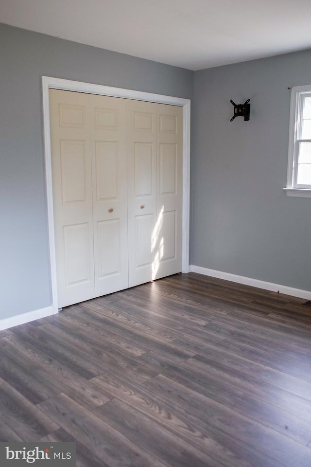 unfurnished bedroom with dark hardwood / wood-style flooring and a closet