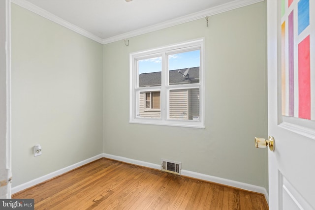 empty room featuring crown molding and wood-type flooring