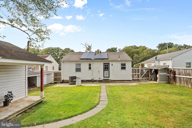 rear view of house with a patio area, a yard, a deck, and solar panels