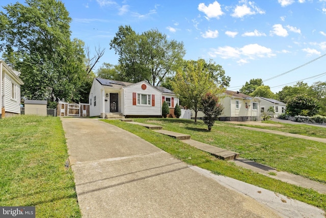 bungalow featuring roof mounted solar panels, driveway, a front yard, and fence