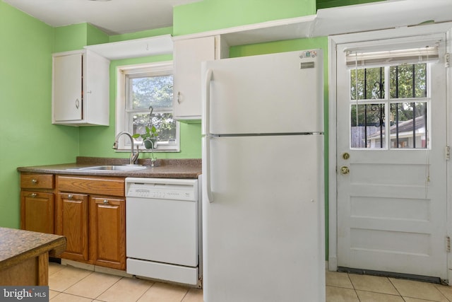 kitchen with light tile patterned floors, white appliances, and sink