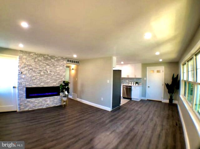 unfurnished living room featuring dark wood-type flooring and a stone fireplace