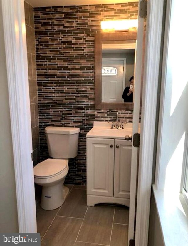 bathroom with tile patterned flooring, vanity, toilet, and backsplash