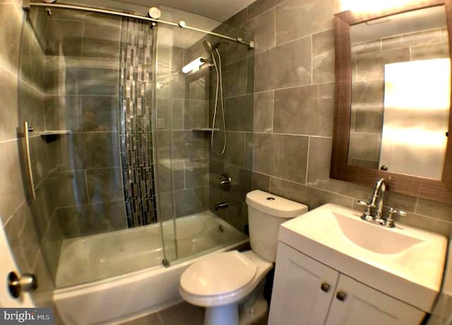 full bathroom with vanity, combined bath / shower with glass door, tasteful backsplash, tile walls, and toilet