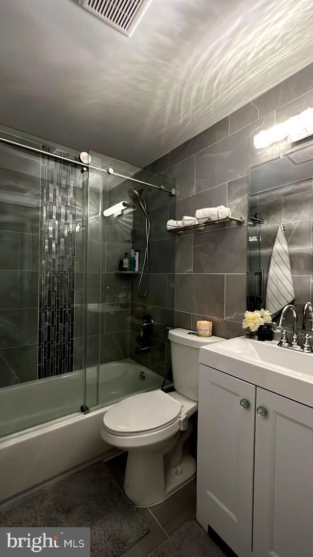 full bathroom featuring tile walls, toilet, vanity, and tile patterned floors