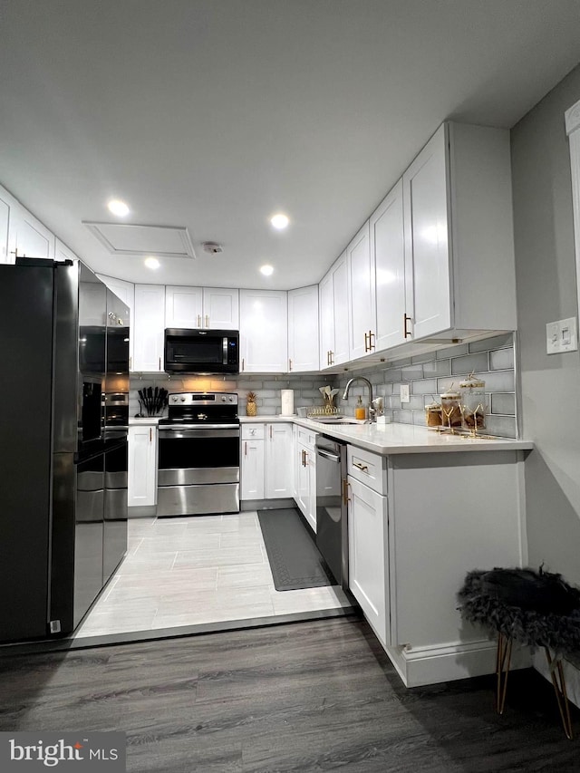 kitchen featuring sink, hardwood / wood-style floors, appliances with stainless steel finishes, and white cabinetry