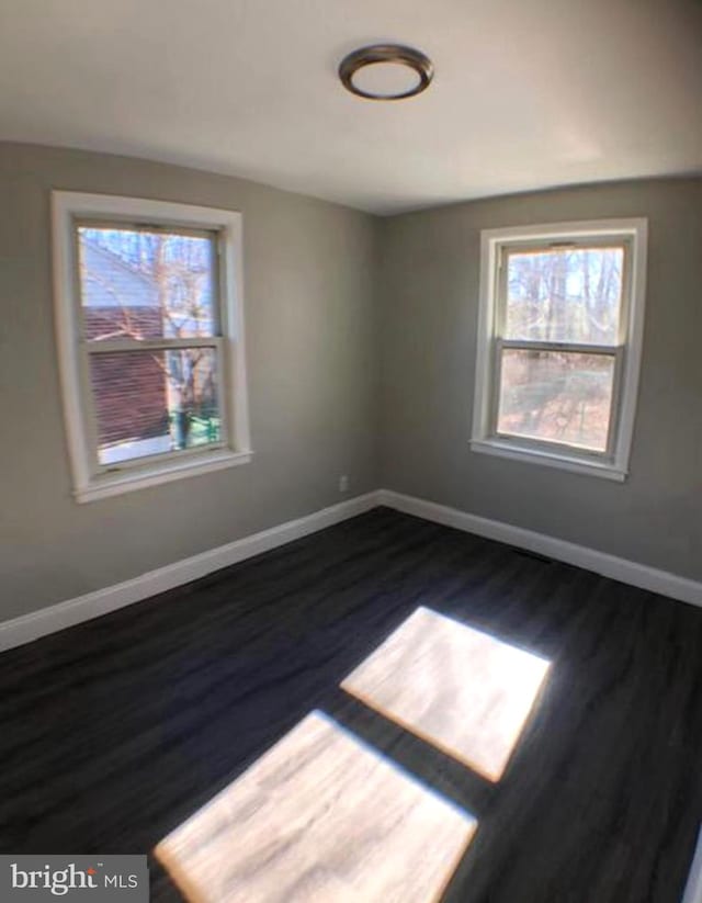 empty room featuring a healthy amount of sunlight and dark hardwood / wood-style floors