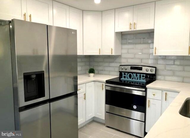 kitchen with appliances with stainless steel finishes, light stone counters, backsplash, and white cabinets