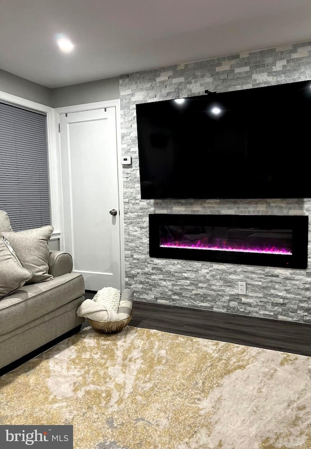 living room with a stone fireplace and wood finished floors