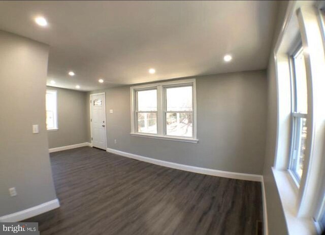 unfurnished room featuring plenty of natural light and dark hardwood / wood-style floors