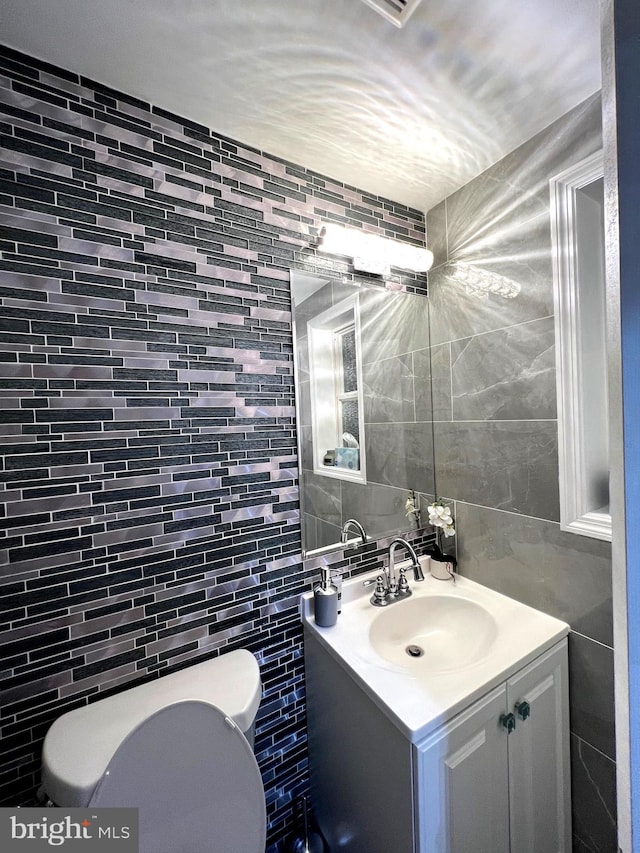 bathroom with vanity, tile walls, and toilet