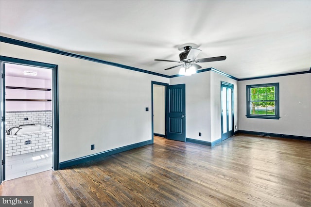 spare room with baseboards, ornamental molding, ceiling fan, and dark wood-style flooring