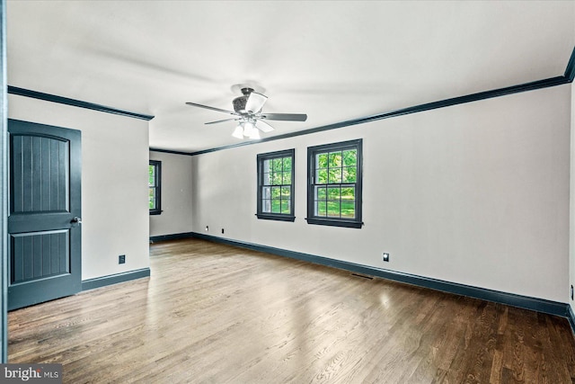 spare room featuring visible vents, baseboards, a ceiling fan, wood finished floors, and crown molding