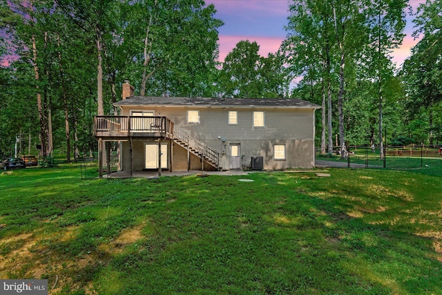 back of property at dusk featuring central AC unit, a lawn, a chimney, stairway, and a deck