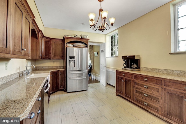 kitchen featuring light stone counters, sink, pendant lighting, a notable chandelier, and stainless steel appliances