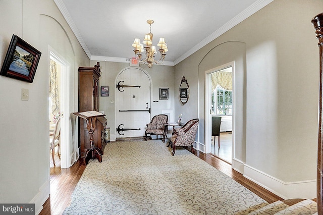 sitting room featuring ornamental molding, hardwood / wood-style floors, and an inviting chandelier