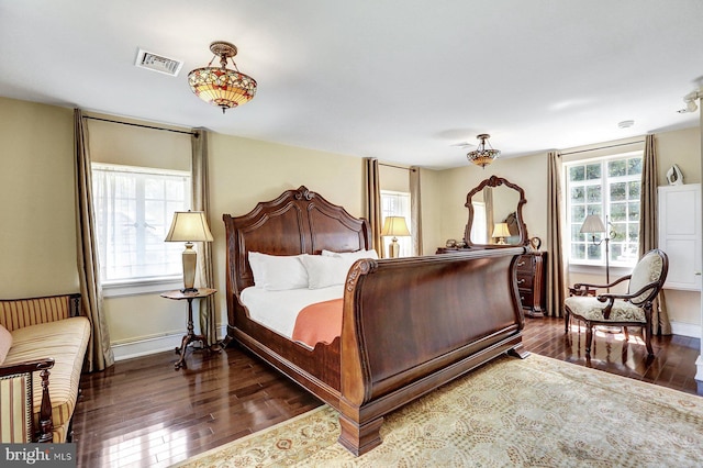 bedroom featuring multiple windows and dark hardwood / wood-style flooring