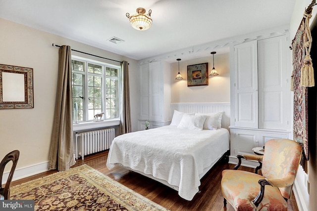 bedroom with dark hardwood / wood-style flooring and radiator