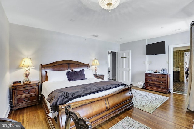 bedroom with ensuite bathroom and dark wood-type flooring