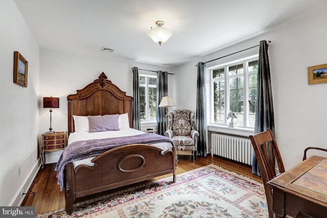 bedroom featuring radiator heating unit and dark hardwood / wood-style flooring