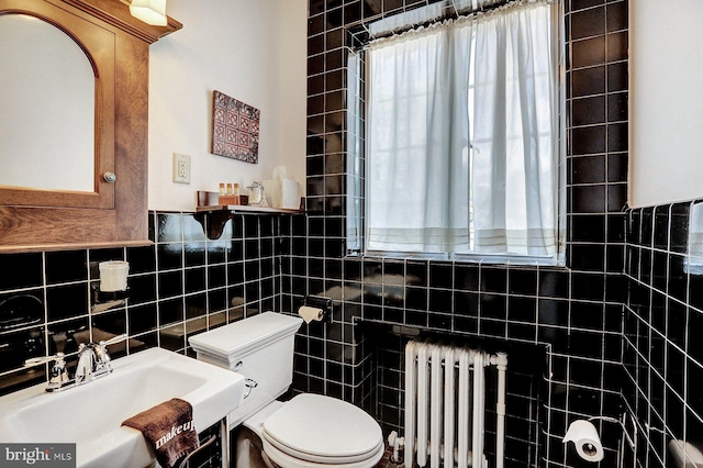 bathroom featuring tasteful backsplash, sink, radiator, toilet, and tile walls