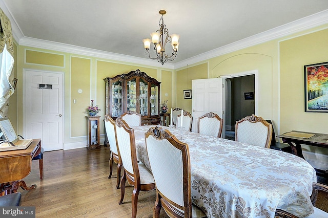 dining space with hardwood / wood-style floors, a notable chandelier, and crown molding