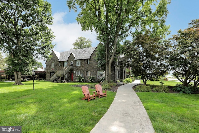 view of front of home featuring brick siding, stone siding, and a front yard