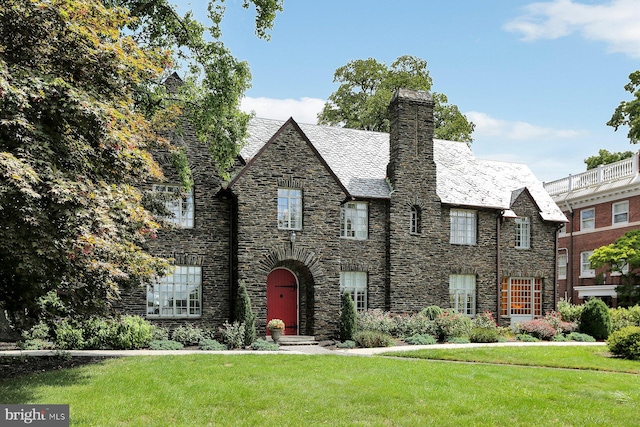 tudor-style house featuring a front yard