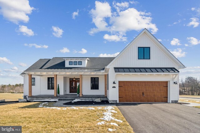 modern inspired farmhouse with a garage, a porch, and a front yard