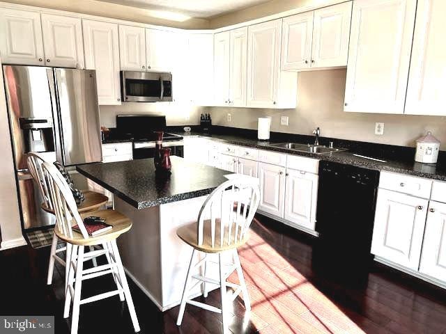 kitchen with black appliances, white cabinetry, a kitchen island, and dark hardwood / wood-style flooring