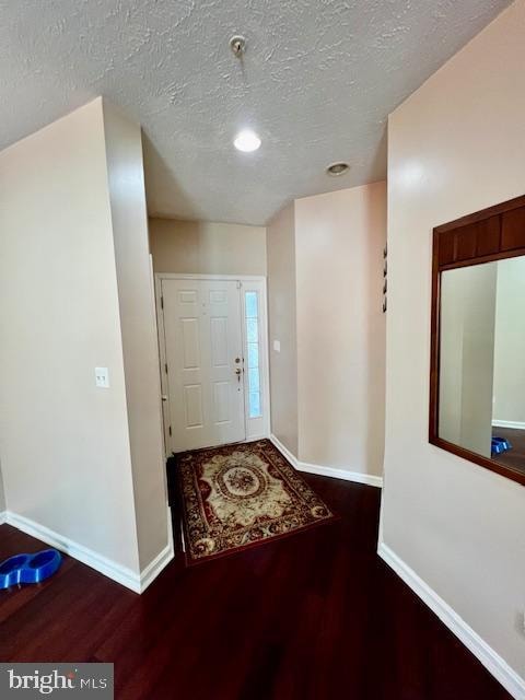 foyer featuring a textured ceiling and dark wood-type flooring