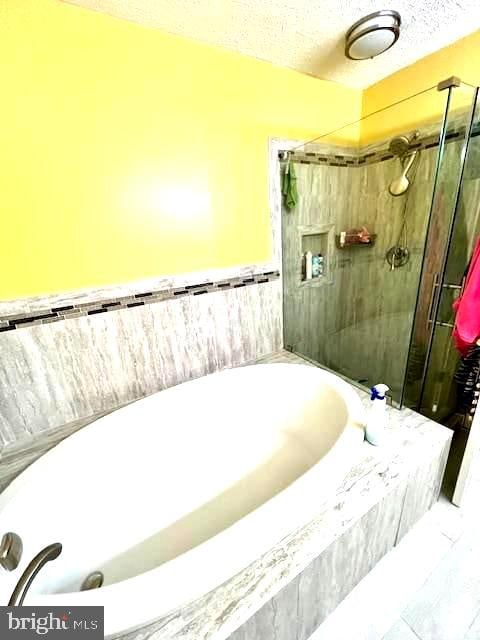 bathroom with shower with separate bathtub, a textured ceiling, and tile patterned floors