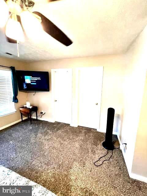 unfurnished living room featuring ceiling fan and carpet flooring